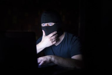 Dizüstü bilgisayar ile siyah maskeli hacker