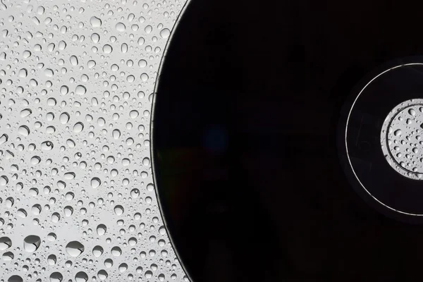 Черный диск на фоне капель воды — стоковое фото