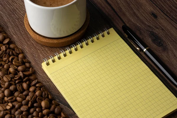 白いコーヒーカップ 空白のノート ペンとローストコーヒー豆 — ストック写真