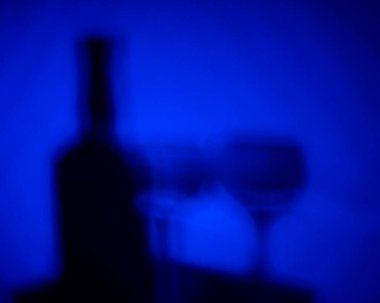 Koyu mavi arka planda şişe ve gözlüğün gölgeleri