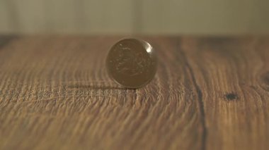 Bozuk para ağır çekimde ahşap masada dönüyor.
