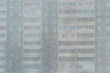 Windows of apartment building are barely visible during a snowstorm in city clipart