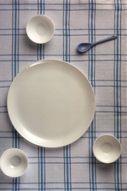 Damalı masa örtüleri üzerinde büyük ve boş yuvarlak bardaklar ile büyük bir tabak