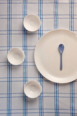 Yuvarlak tabak ve boş yuvarlak bardaklar kareli masa örtüleri