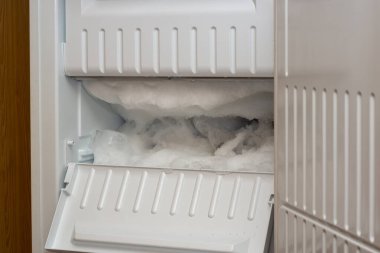 Fridge freezer is covered with an ice and snow clipart