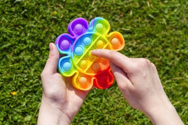 Sivilce önleyici oyuncağın lastik sivilceleri yeşil çimlerin üzerinde patlıyor.