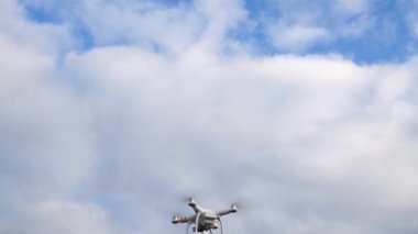 Bulutlu gökyüzündeki beyaz dron hediye kutusuyla uçuyor.
