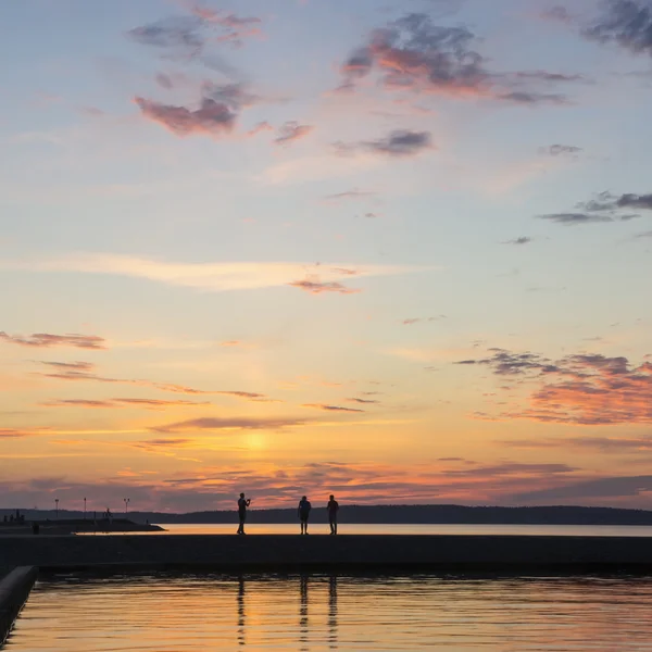 La gente siluetas en el muelle del lago por la noche —  Fotos de Stock