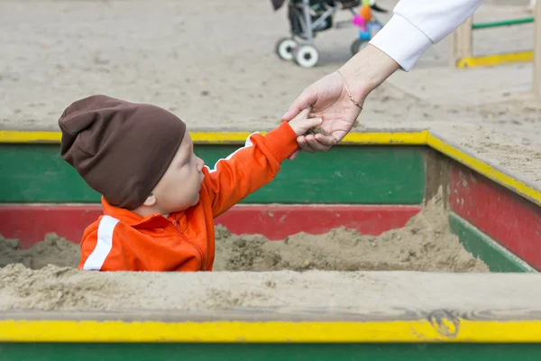 Klein kind in sandbox geeft zand — Stockfoto