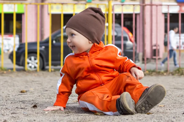 Piccolo ragazzo divertente siede a terra — Foto Stock