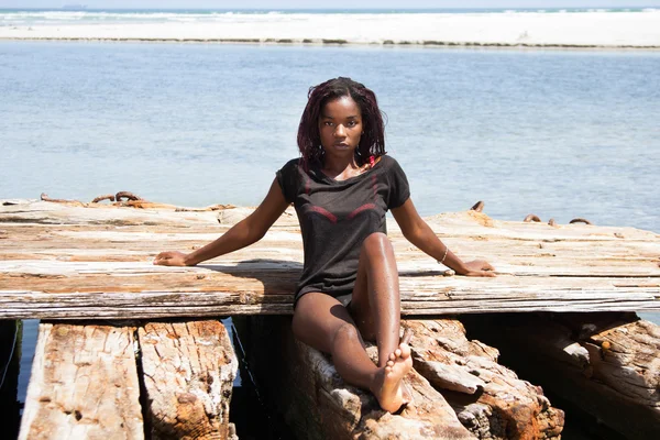 Schöne afrikanische Frau sitzt am Strand — Stockfoto