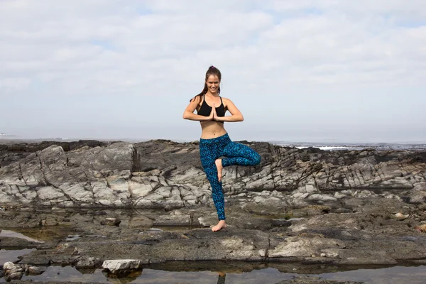 Woman relaxing by practicing yoga near the sea — Stock Photo, Image