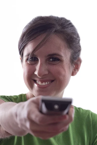 Mujer sonriendo en un televisor mientras señala un mando a distancia — Foto de Stock