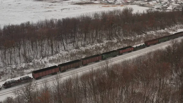A train with open wagons travels through winter Russia. A train with wagons transports metal on rails. russian train winter