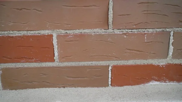 Worker builds a wall of colored brick. Worker in Close up of industrial bricklayer installing bricks and mortar cement brick on construction site