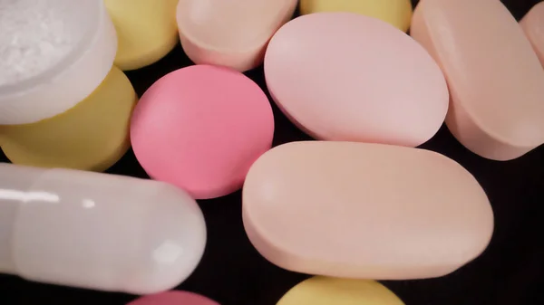 Tablets of different sizes close-up. Medicines tablets, capsules, pills of different kinds, sizes and colors, piled up in bulk.Colored vitamin close up.