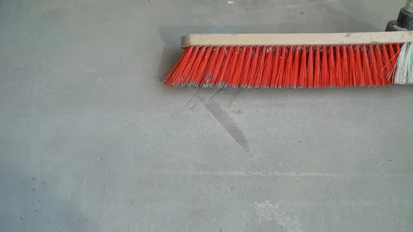 A worker brushes the concrete floor before laying. Cleaning the floor with a brush before applying the solution.