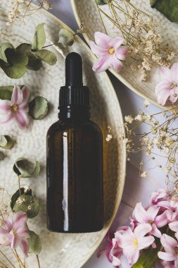 Esans serumu. Koyu pipet şişesi, kozmetik cilt bakımı. Kurumuş bitkiler üst görünüm