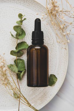 Esans serumu. Koyu pipet şişesi, kozmetik cilt bakımı. Kurumuş bitkiler üst görünüm