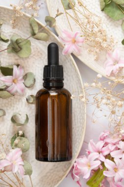 Esans serumu. Koyu pipet şişesi, kozmetik cilt bakımı. Kurumuş bitkiler üst görünüm