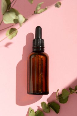 Esans serumu. Koyu pipet şişesi, kozmetik cilt bakımı. Pembe arkaplan.