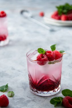 Nane yaprağı ve buz küpleriyle ahududu soğuk kokteyli. Bardakta taze yaz içeceği