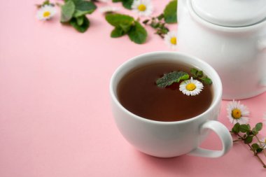 Papatya çiçeği ve nane yapraklı bir fincan bitki çayı.