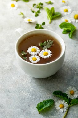 Papatya çiçeği ve nane yapraklı bir fincan bitki çayı.