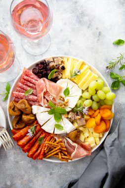 Şarküteri tabağı, çeşit çeşit peynir ve salam, prosciutto, kurutulmuş meyve, incir, kayısı, kızılcık servisi, iki kadeh şarap.