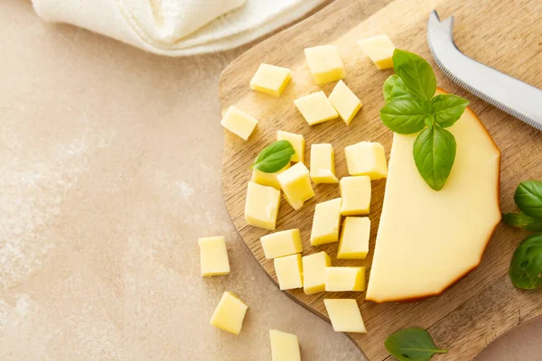 Smoked cheese on cutting board with basil, sliced cheese, dairy product