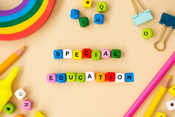 Special education words, child care, disability concept. Colorful office suplies flat lay, wooden cubes