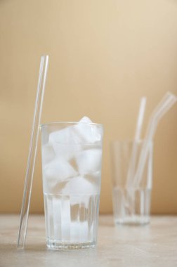 Kamış ve bardakla birlikte bir bardak su ve buz. Çevre dostu pipetler