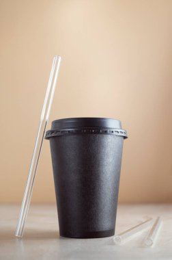 Tek kullanımlık kahve fincanı, arka planda cam pipetle izole edilmiş. Çevre dostu bardaklar, içkileri alın.