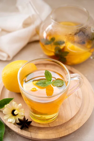 Delicious fruit tea with mint, herbs, lemons and orange slices. Glass teacup and glass cup of hot tea.