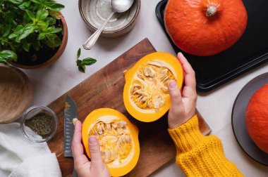 Taze balkabağı. Kesme tahtasında balkabağını dilimlemek, sonbahar yemeklerini hazırlayan kadın elleri. Fırında kabak ya da tereyağı, üst manzara..
