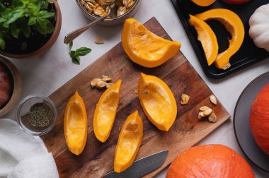 Kesme tahtasındaki taze, turuncu balkabağı dilimlerinin üst görüntüsü. Tereyağlı çorba, turta ya da sonbahar yemeği için yemek malzemeleri.