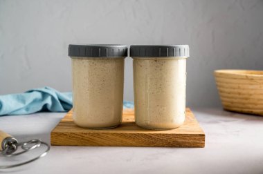 Taze yapraklı mayalı ekmek, cam kavanozlarda başlangıç, parlak arka plan.