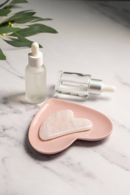 Gül kuvars şase aleti ve yağ şişeleri, yüz masajı aracı, güzel soyut fotoğraf.