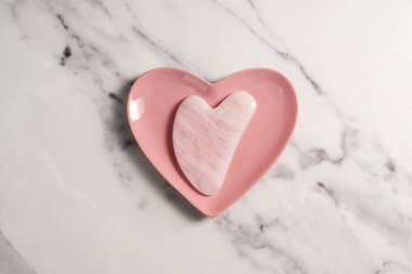 Gül kuvars gua sha aracı yüz masajı aracı, güzellik soyut fotoğraf.