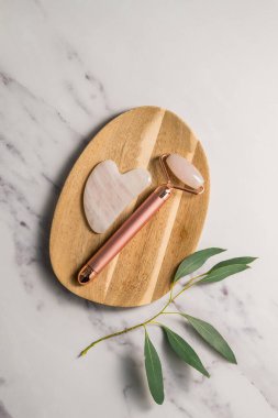 Rose Quartz gua sha aracı ve yüz masajı silindiri, güzel soyut fotoğraf. Üst görünüm