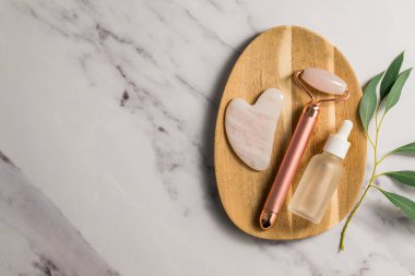 Rose Quartz gua sha aracı ve bambu tepside yüz masajı silindiri, güzellik soyut fotoğrafı. Üst görünüm
