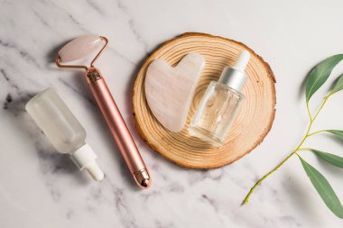 Rose Quartz gua sha aracı ve bambu tepside yüz masajı silindiri, güzellik soyut fotoğrafı. Üst görünüm