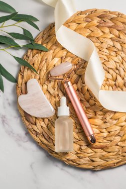 Rose Quartz gua sha aracı ve bambu tepside yüz masajı silindiri, güzellik soyut fotoğrafı. Üst görünüm