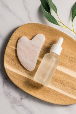 Gül kuvars aleti ve yağ şişesi ahşap tepside, yüz masajı aleti, güzel soyut fotoğraf. Boşluğu kopyala