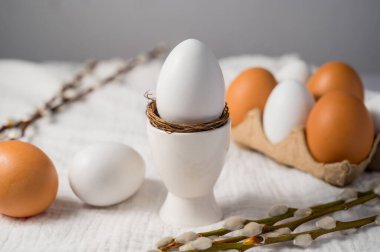 Paskalya geçmişi. Söğüt dalları, seramik tutacağında beyaz yumurta. Bahar geldi. Asgari.