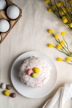 Paskalya bayramı pastası, kremalı, şekerli ve yumurtalı. Beyaz yumurtalar ve bahar, sarı çiçek dalları.