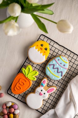 Paskalya bayramı renkli kurabiyeler tavşanı, havuç, yumurta, yumurta tabağında yumurta şekeri olan civciv. Beyaz bahar laleleri.