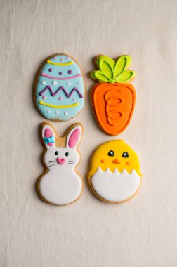 Paskalya bayramı renkli kurabiyeler: tavşan, havuç, yumurta, tekstil arka planında izole edilmiş civciv. Üst görünüm.