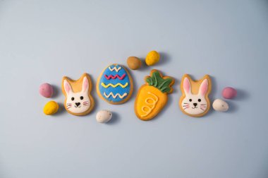 Paskalya bayramı arkaplanında paskalya kurabiyeleri: tavşancık, havuç ve yumurta ile mini çikolata şekeri, kopyalama alanı