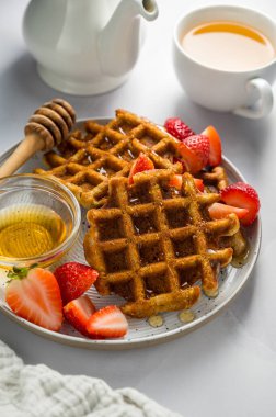 Çilekli Belçika waffle 'ı, bir fincan çay ve taze meyve. Ev yapımı kahvaltı ya da tatlı.